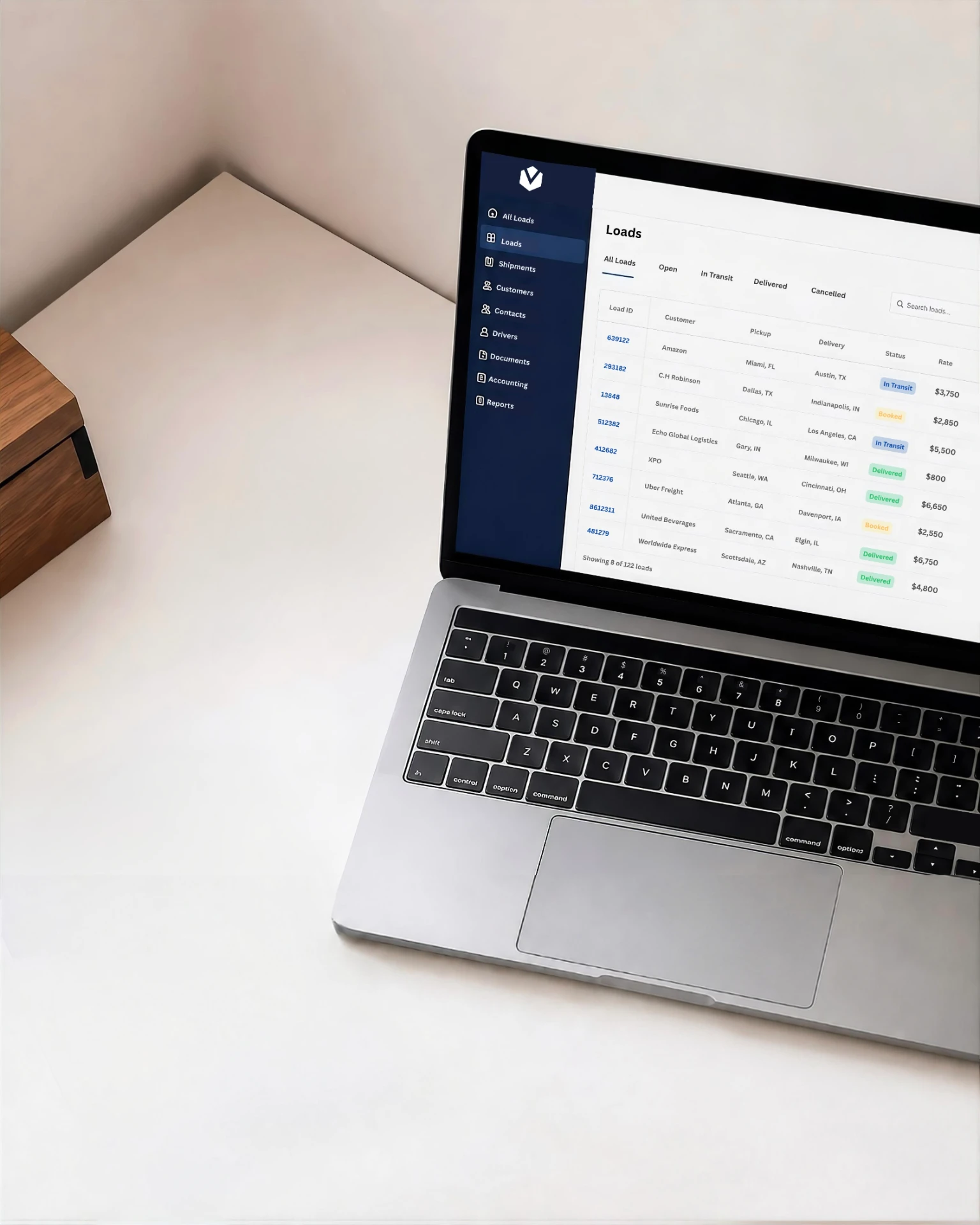 Laptop showing a Valen Logistics load board with lanes, statuses, and rates