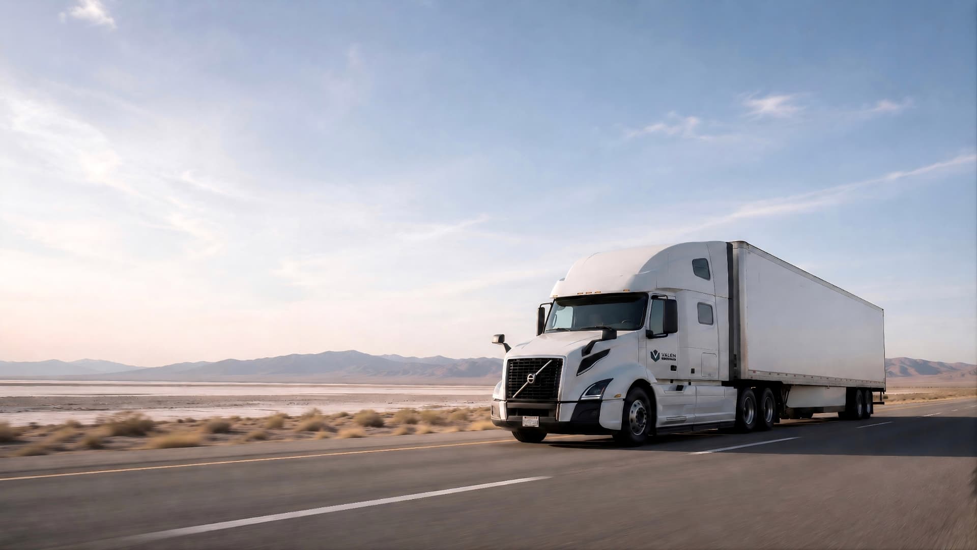 A dry van semi truck on an open American highway at golden hour